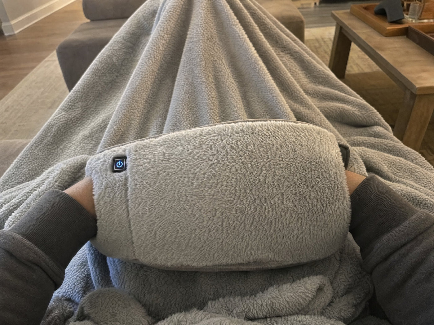 A customer photo of hands tucked into the FuzzyPouch on a couch